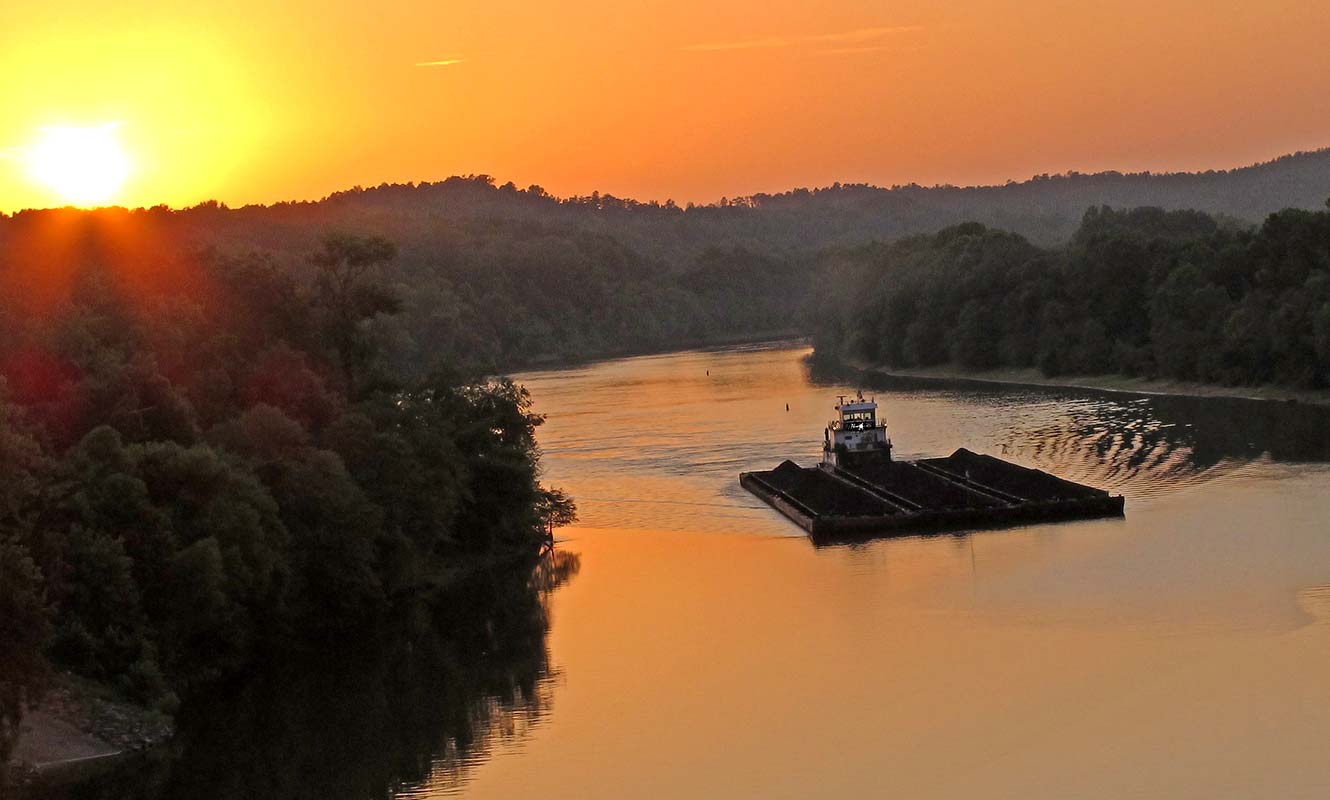 A barge going down the river at sunset