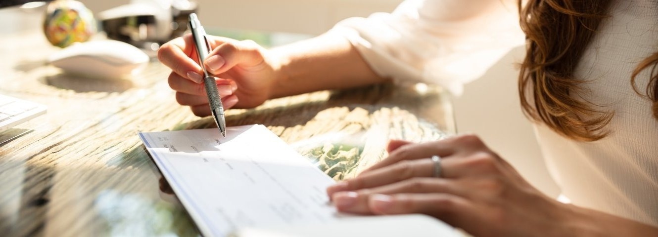 woman with pen signing check