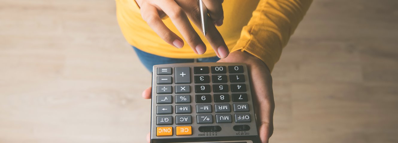 woman using a calculator wearing a yellow shirt
