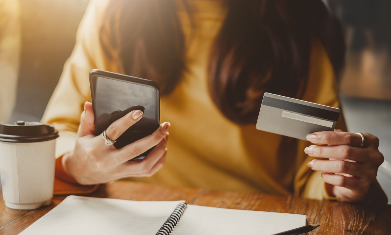 Close up of a woman's hands holding a cell phone and a credit card.