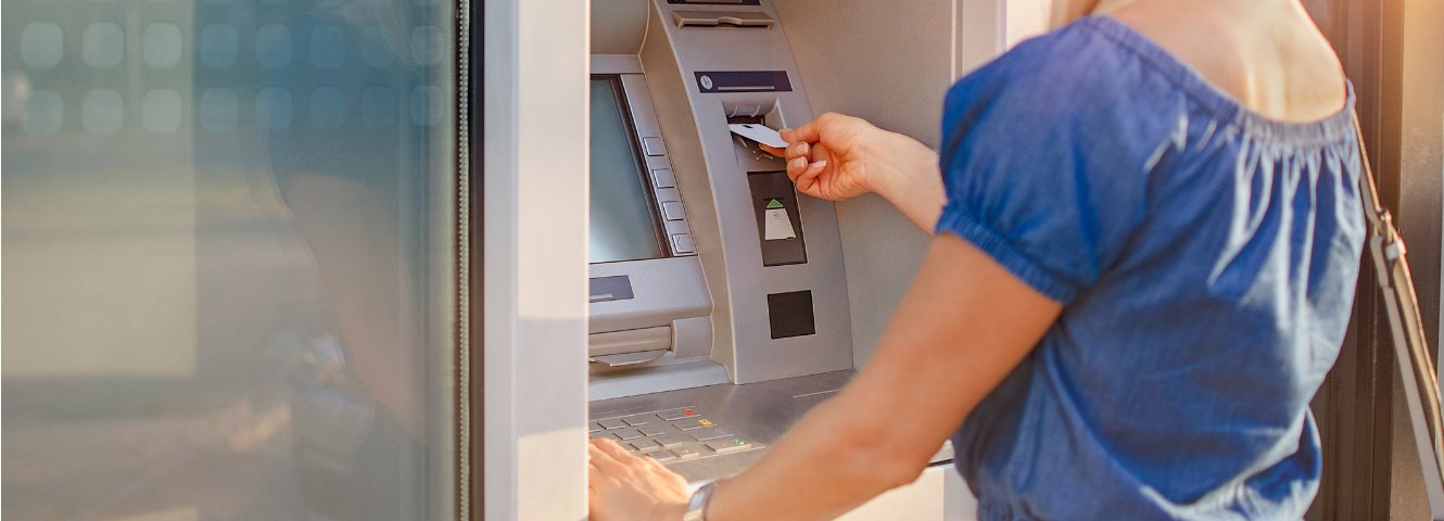 woman in blue shirt using atm machine