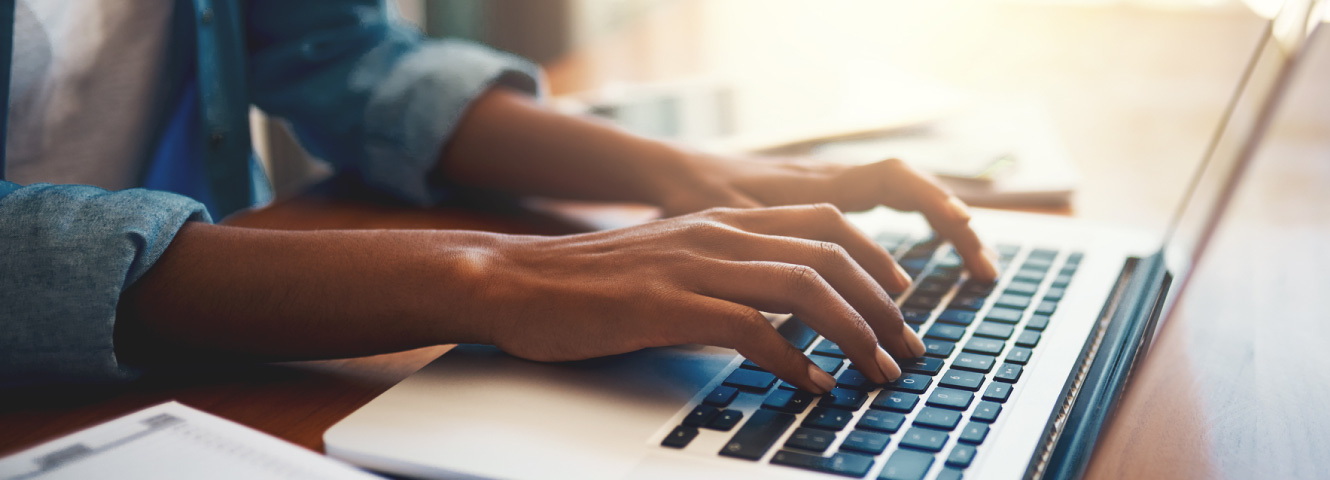 Close up of someone's hands typing on a modern laptop.