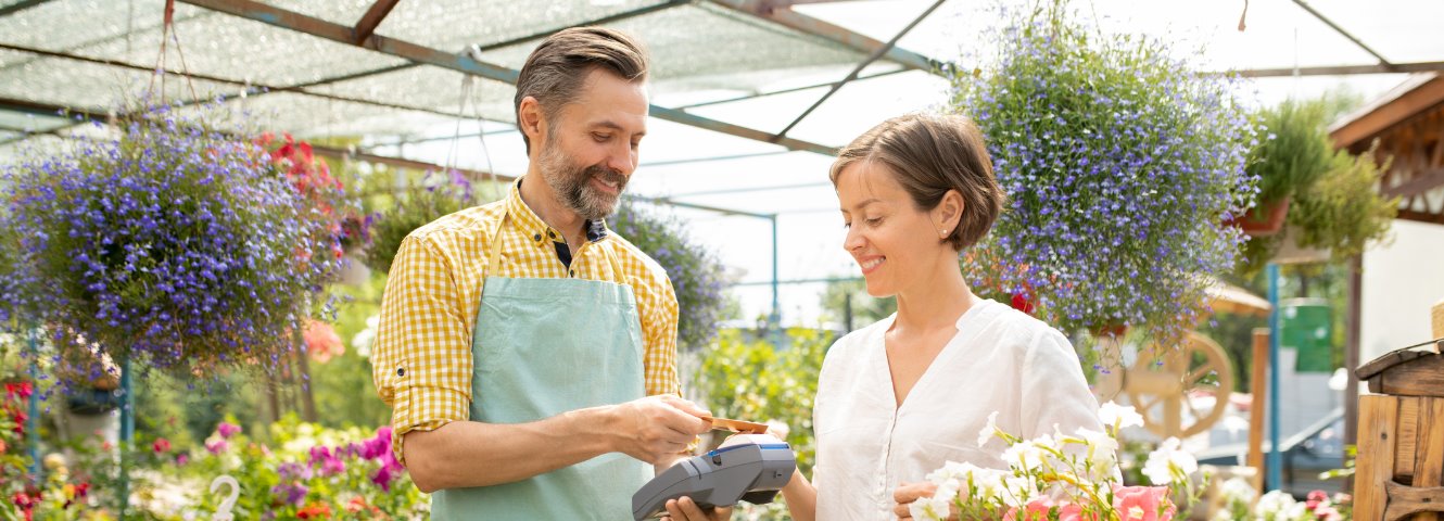 man and woman in greenhouse-woman paying with a credit card