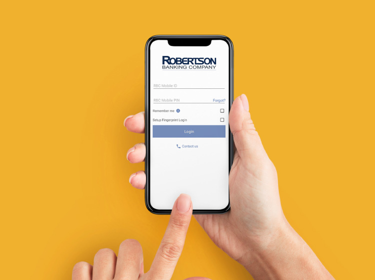 Close up of someone's hands holding a phone. The phone's screen shows Robertson Banking's online banking login screen.