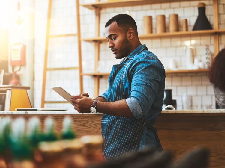 Man in apron looking at a tablet.